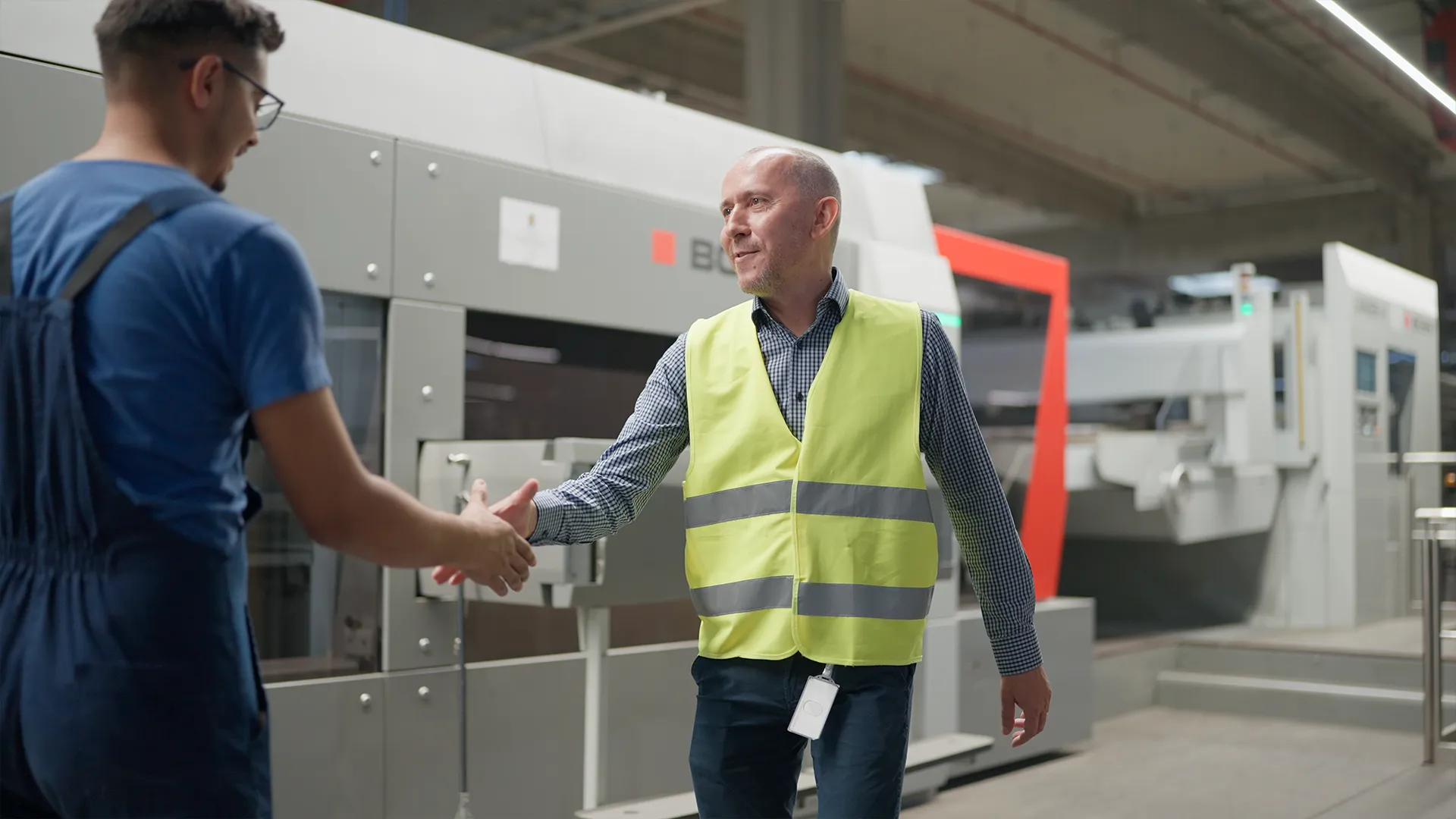Mihai Radu stringe la mano a un operatore davanti alla fustellatrice BOBST